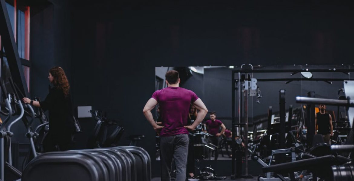 Man in a gym with fitness equipment, highlighting a healthy lifestyle.