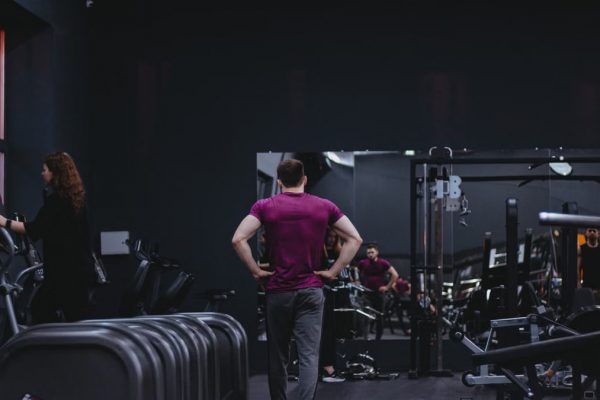 Man in a gym with fitness equipment, highlighting a healthy lifestyle.